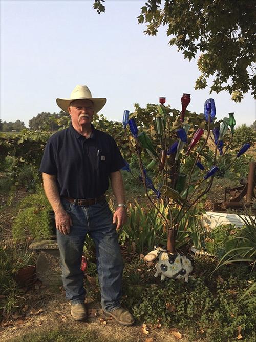 Man in hat next to sculpture of colored glass. 
