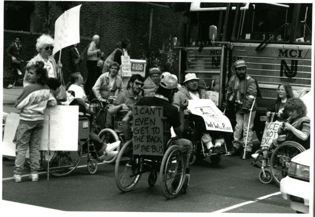 People in wheelchairs with protest signs People in wheelchairs with protest signs