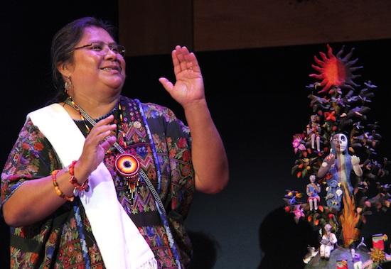 Veronica Castillo mid-conversation next to one of her tree of life sculptures on stage at the folk arts masters concert celebration