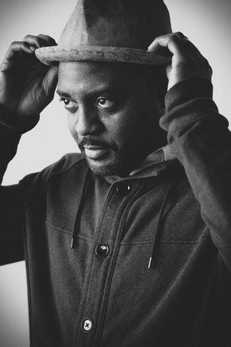 Reginald Dwayne Betts Man looking off camera and lifting hat slightly off his head