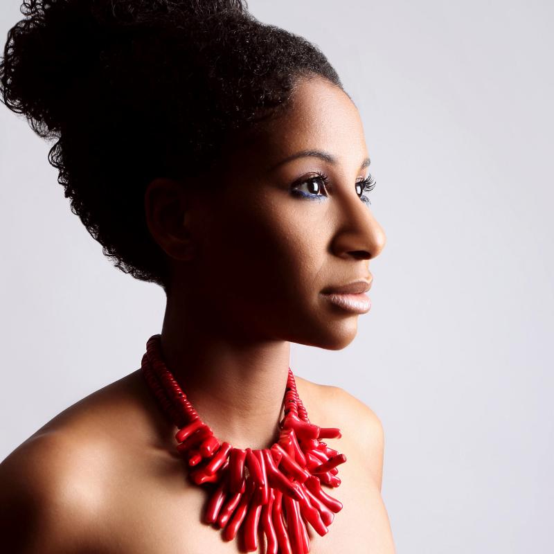 A woman with hair in a bun and red necklace