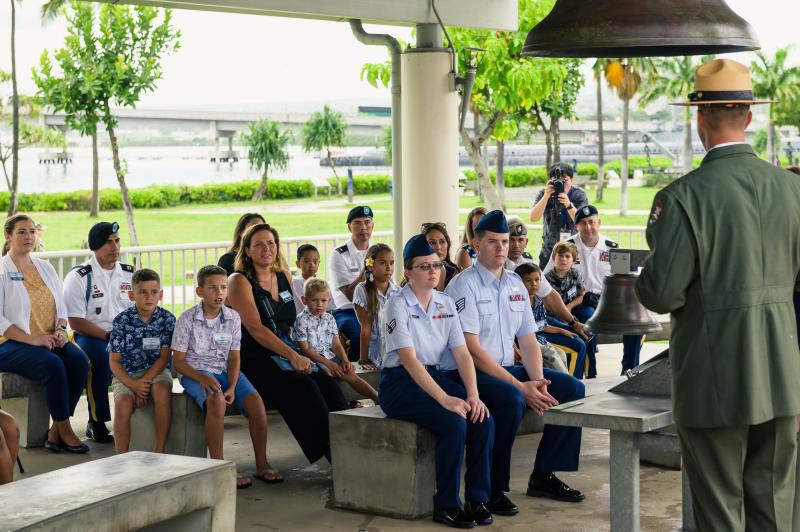 Military families sit on benches outside looking at a National Park Service ranger