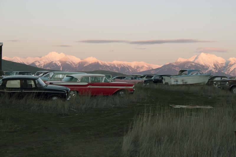 Old abandoned cars against the back drop of snow capped mountains