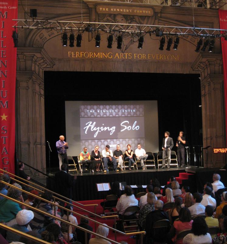 A group of people on stage, three standing and six sitting. 