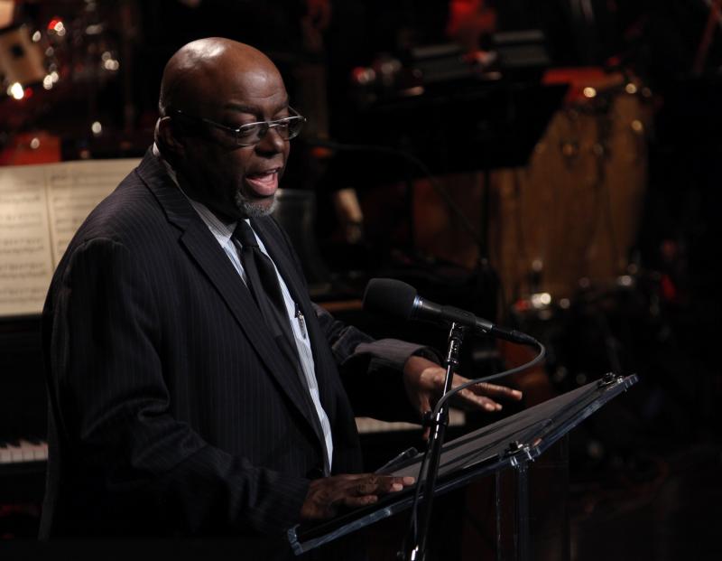 Man in suit speaking at podium on stage. 