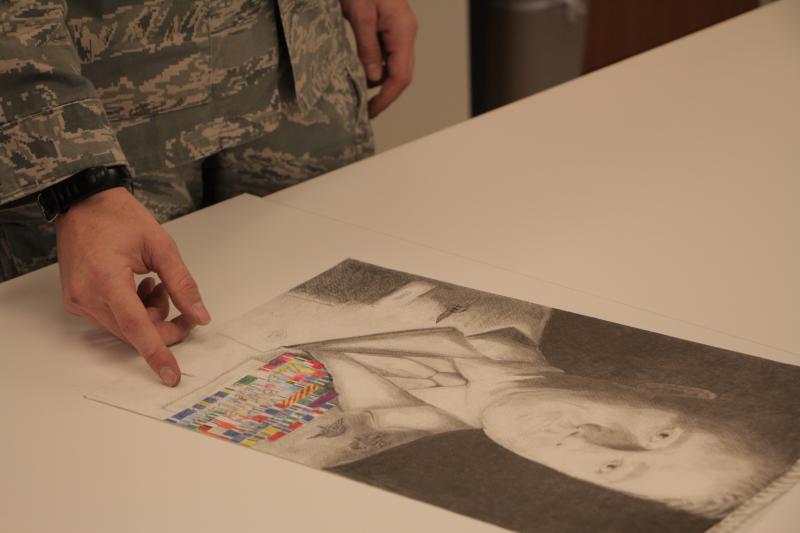 A hand pointing to a drawing of a man.