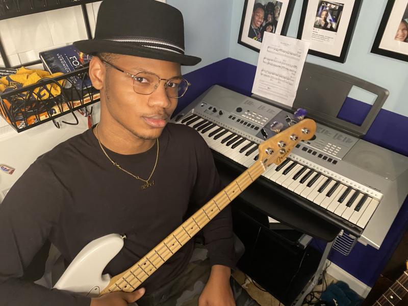 Young man sitting at keyboard and holding a guitar