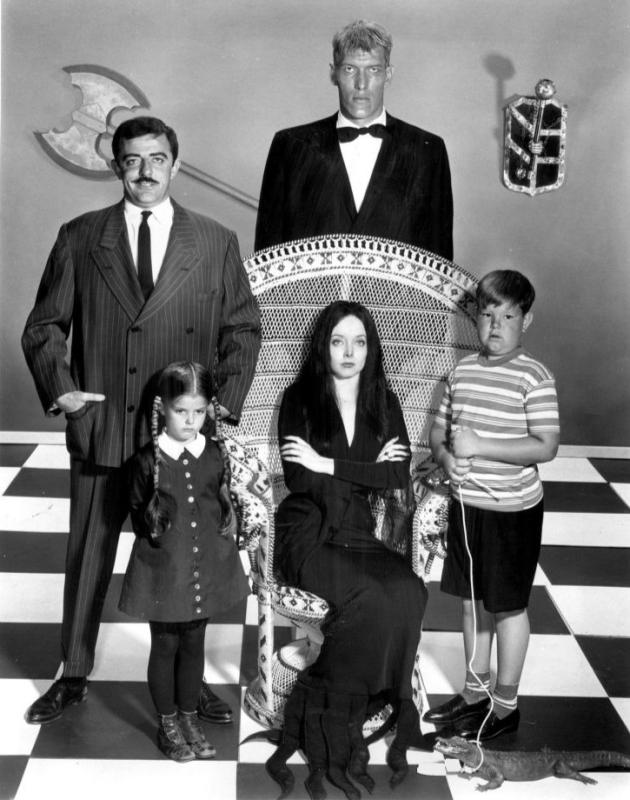 A black-and-white image of three adults (one woman and two men) and two children (one boy and one girl) .