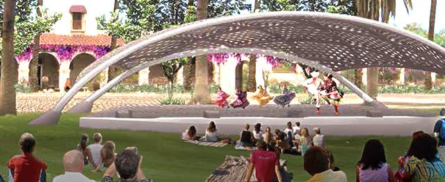 Performers in an outdoor pavilion with a curved top with an audience seated in the grass