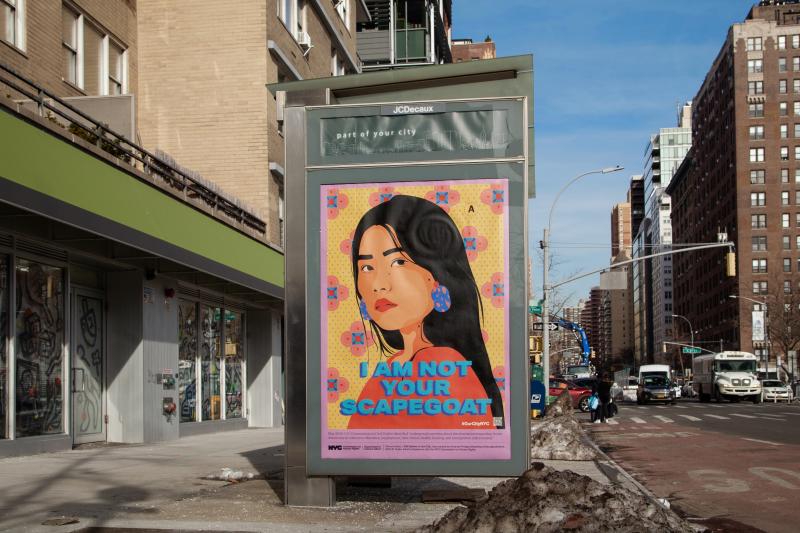 Colorful poster of Asian woman on a bus stop with the caption "I am not your scapegoat."