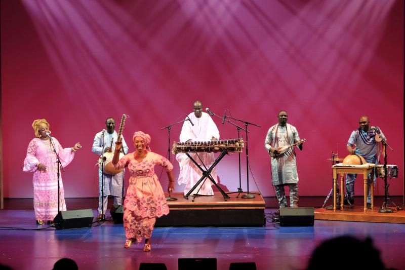 Woman in African garb dancing in front of musical band