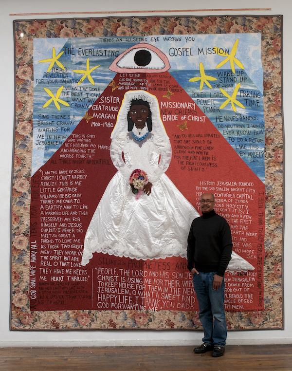 Man standing in front of a large quilt.