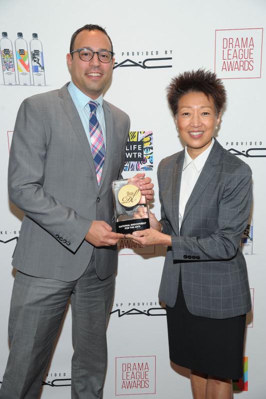 a white man and an Asian American woman hold a trophy