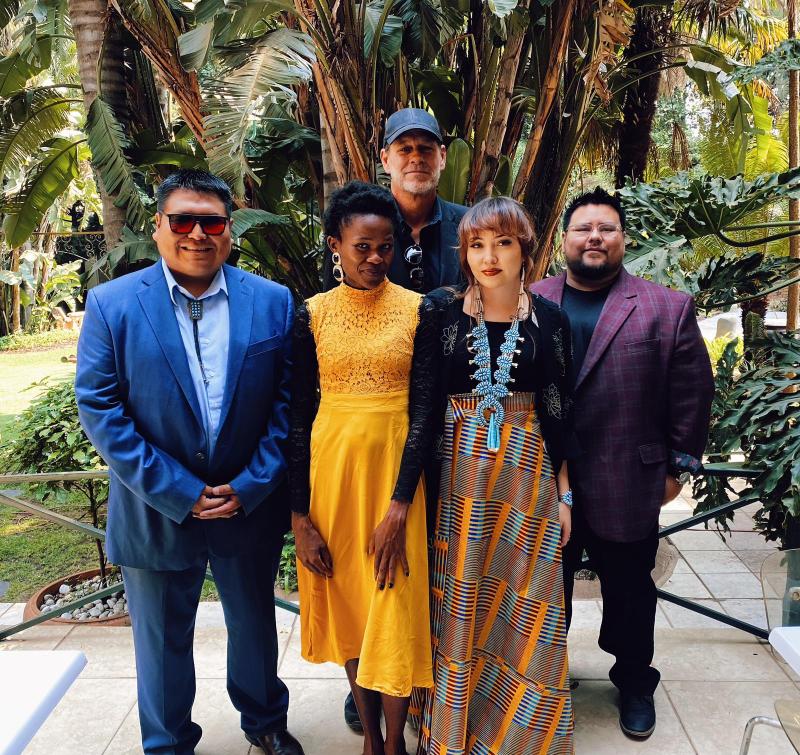 a group of five people in front of a grove of trees