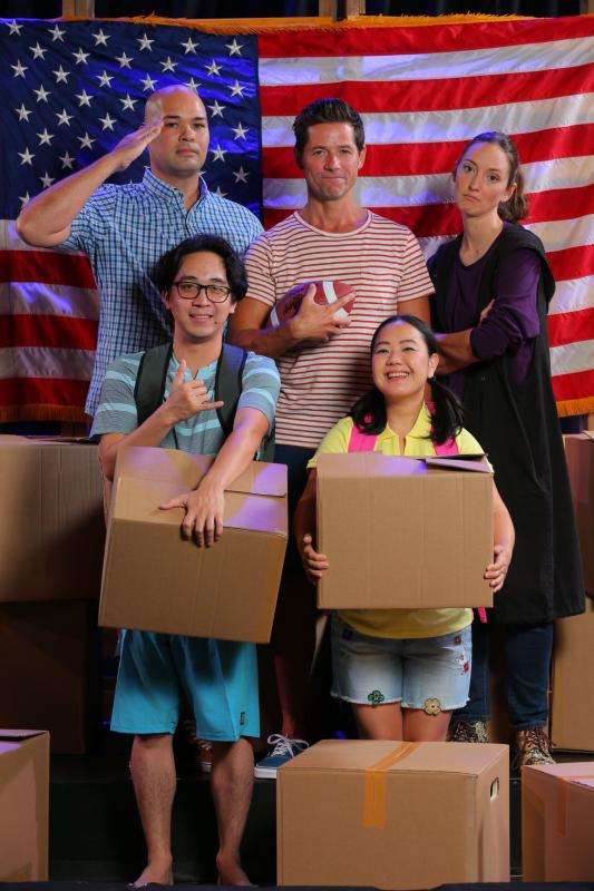 Home of the Brave Actors portraying a family hold cardboard boxes while standing in front of an American flag as one salutes