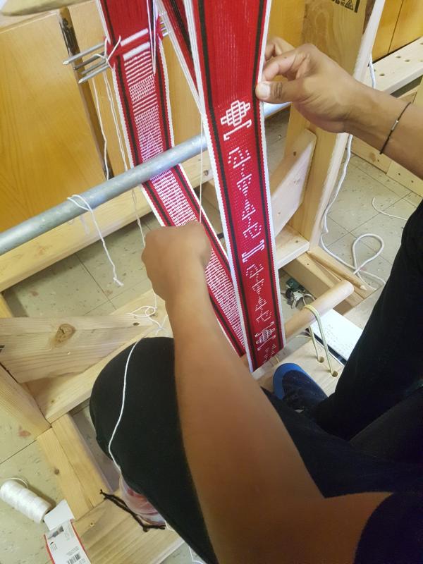 Hopi belt weaving Hands are seen weaving a red belt with Hopi symbols