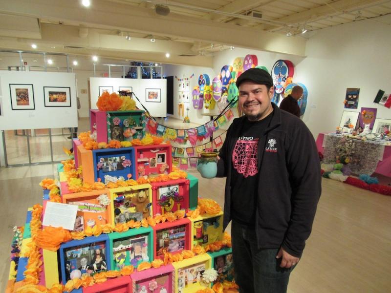 a man stands next to an ofrenda