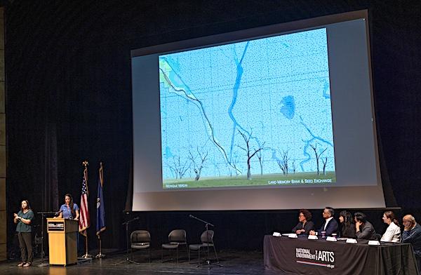 Wide shot of a presentation at the Council meeting with a large slide projection on a sceeen