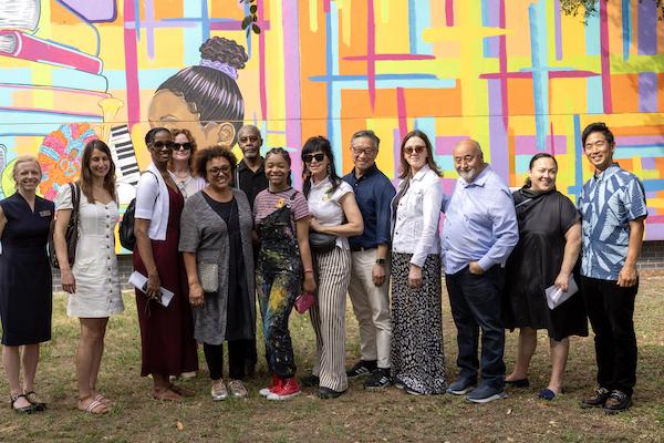 Large group of people standing in front of a large mural