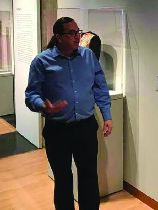 Man in blue shirt talking and gesturing.