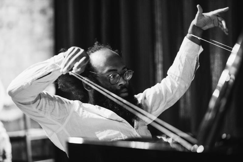 Black man with glasses conducting an orchestra.