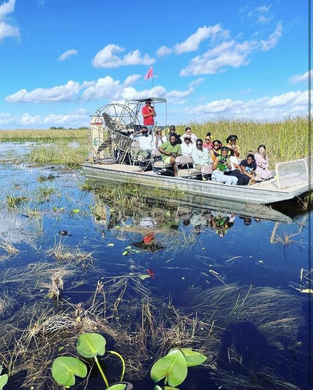 A group of people travel by air boat in a wetland