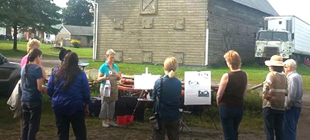 A group of visitors outside listening to an artist disuss her work