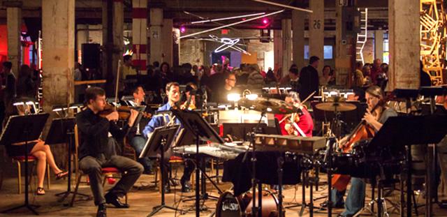 Members of the Dubuque Symphony Orchestra performing at night in a renovated industrial space Urban