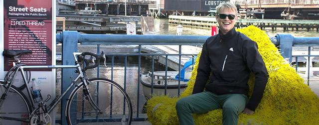 Man sitting outdoors on a seat covered with yellow plant material