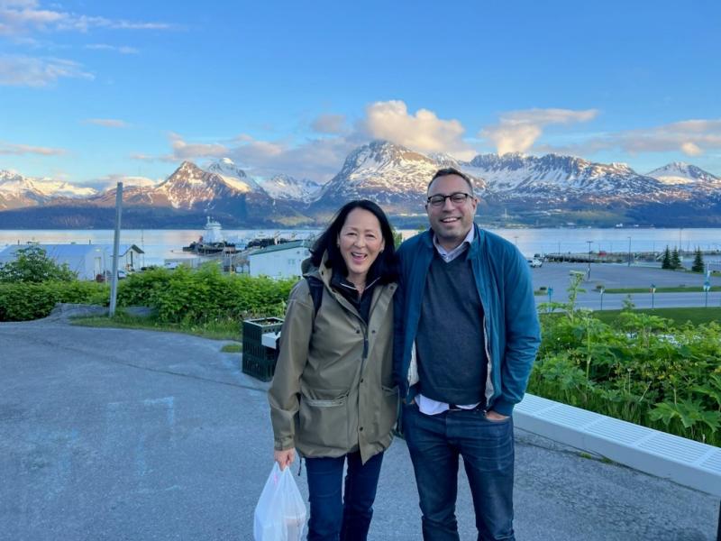 a man and woman stand together with a mountain range in the background