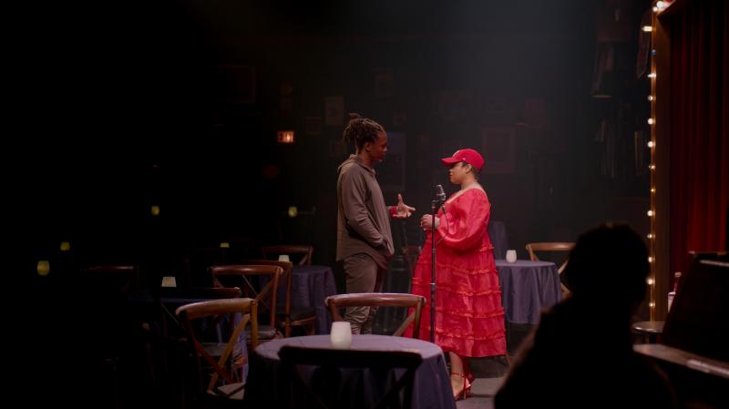a man and woman stand on a set resembling a jazz bar