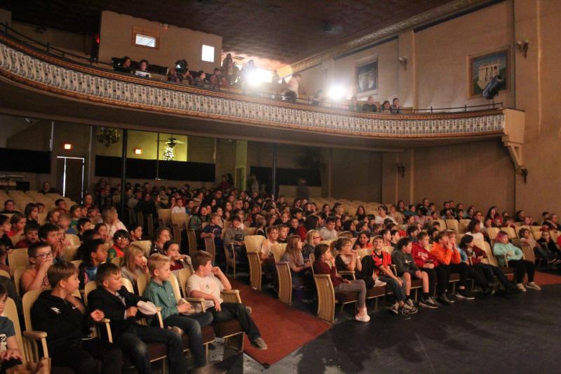 An audience sits in a theater watching a performance.