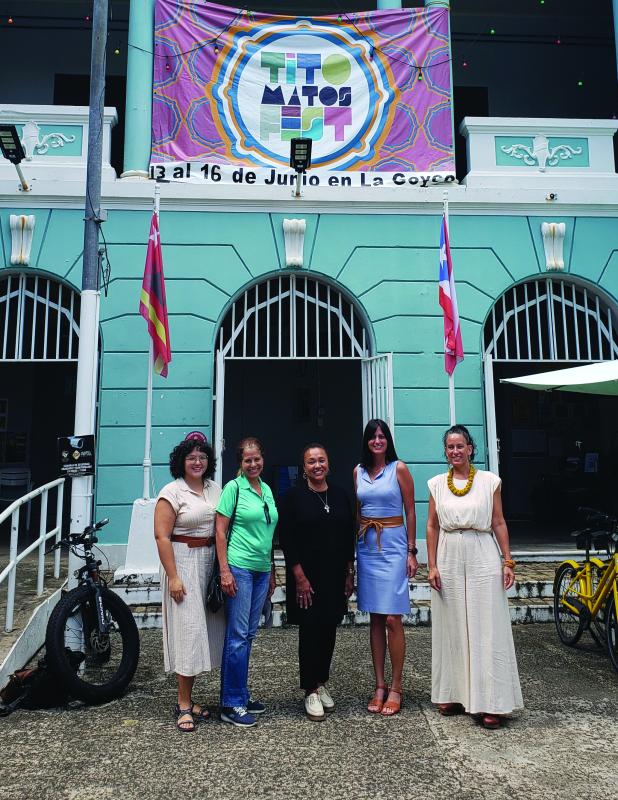 Five women standing in front of a building painted aqua and white.