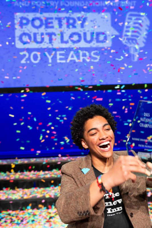 Isavel Mendoza smiling and holding his trophy while confetti falls around him