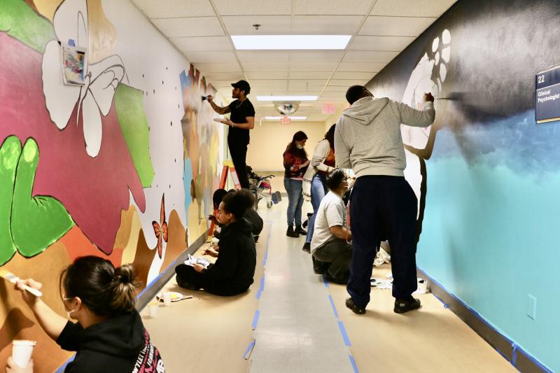 Group of people painting mural on inside walls of building.
