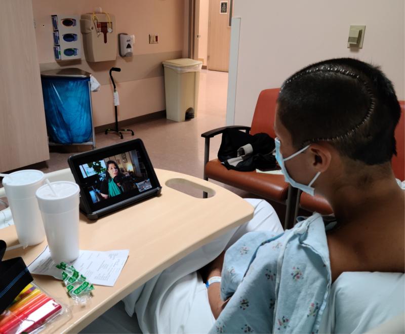 Man in hospital bed watching a lesson on his cell phone.