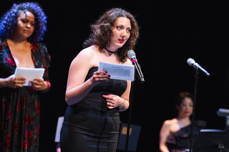 A young woman on stage reading from cards