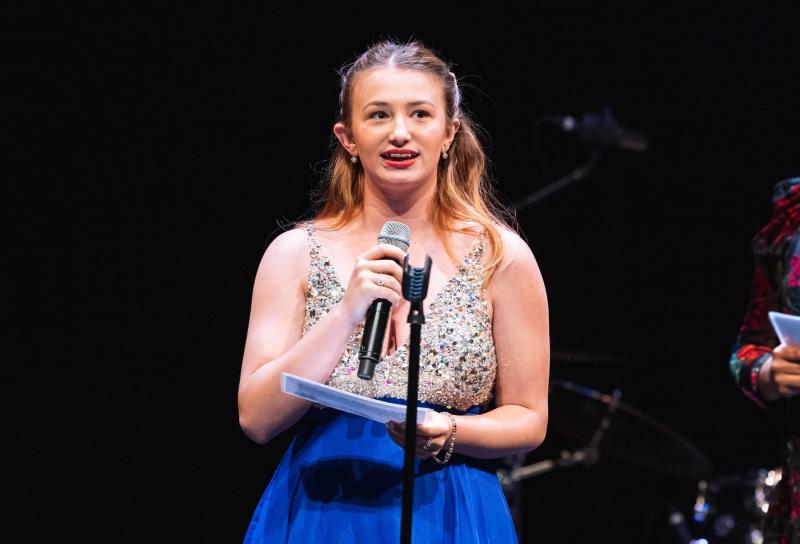 Sydney Gray standing behind a microphone