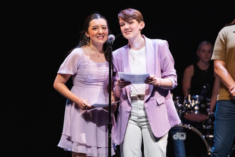 Isabella Nguyen and Maya Johnson on stage behind a mic