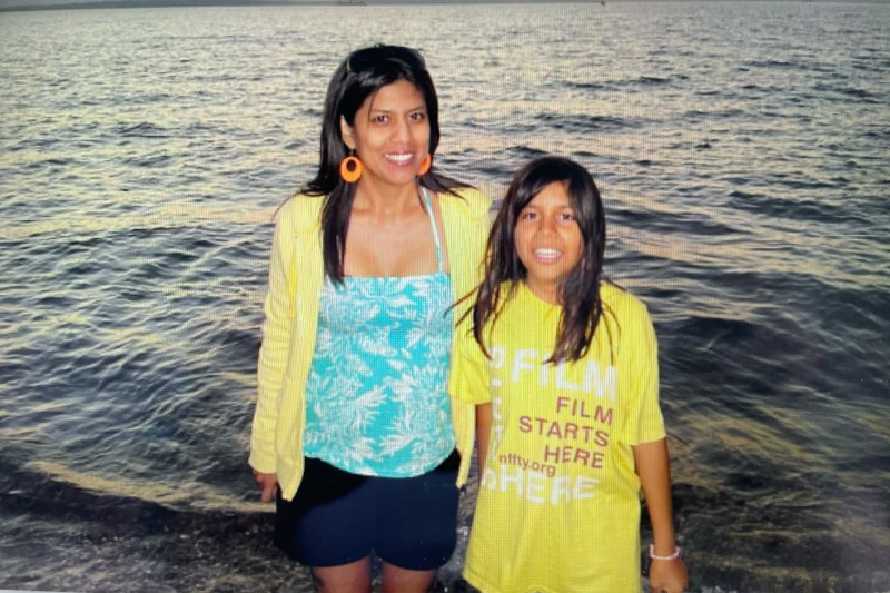 Native woman wearing a yellow hoodie, blue and white shirt, and black shorts (left) and Native boy (right) with long hair and a yellow film festival t-shirt.