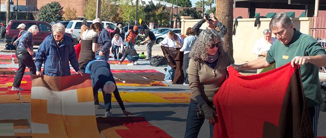 Group of locals spreading out colored blankets in an open town space