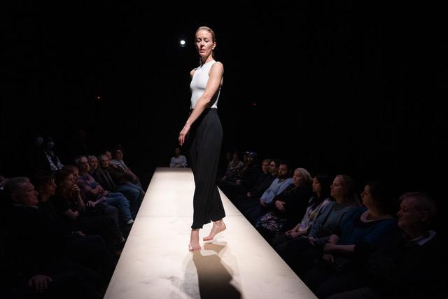 White woman dancing on a stage with audiences surrounding both sides of the stage.