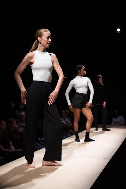 Two white women and a Black woman performing onstage with the audience seated behind the dancers.