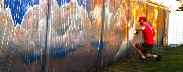 Man working spray paining a large mural