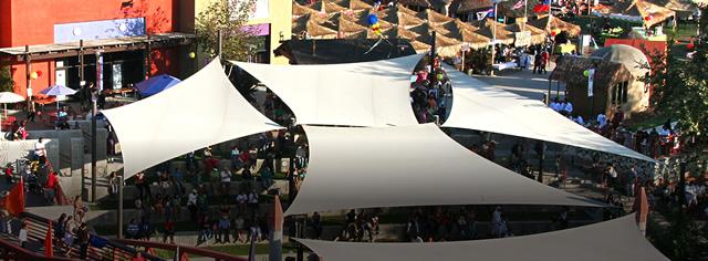 Photo from above looking down at a large outdoor event crowd with a large-paneled tent in the center 