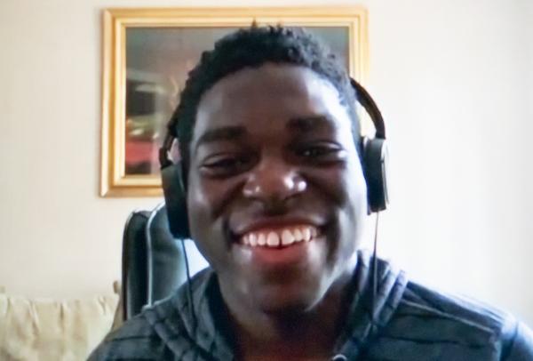 Headshot of a young man with headphones, smiling.