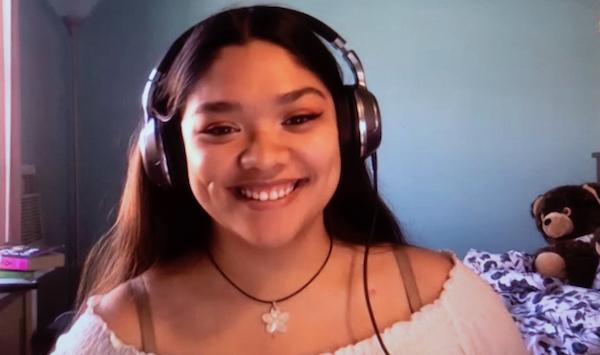 Headshot of a young woman with headphones, smiling.