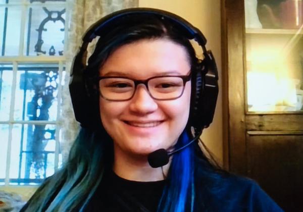 Headshot of a young woman with headphones, smiling.