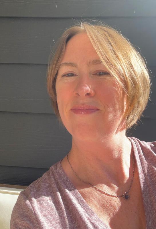 Photo of a White woman wearing a pink shirt and smiling.