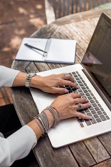 close-up of a woman's hands typing on a laptop